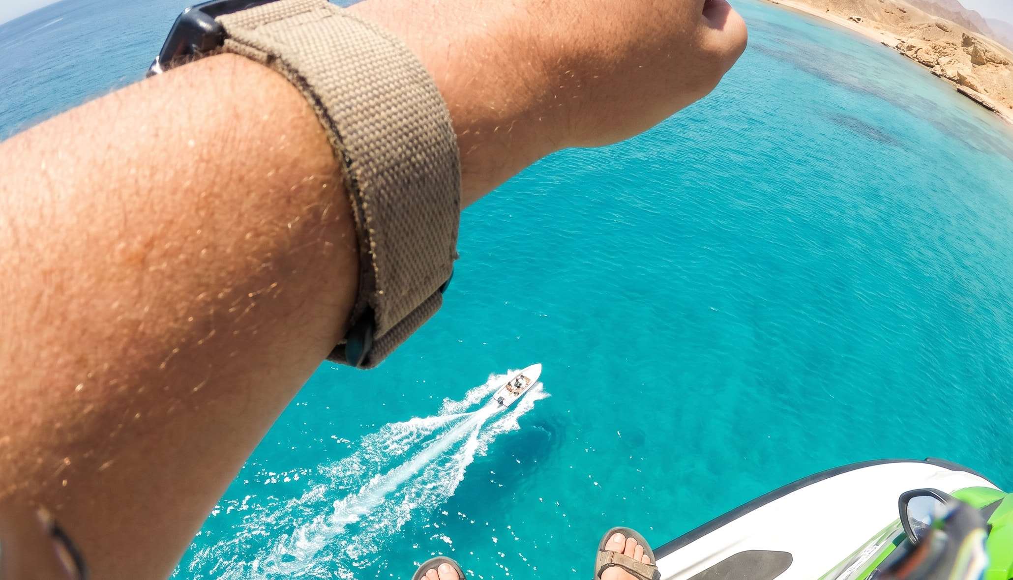 Point-of-view from a parasail over the turquoise reef and the boat below