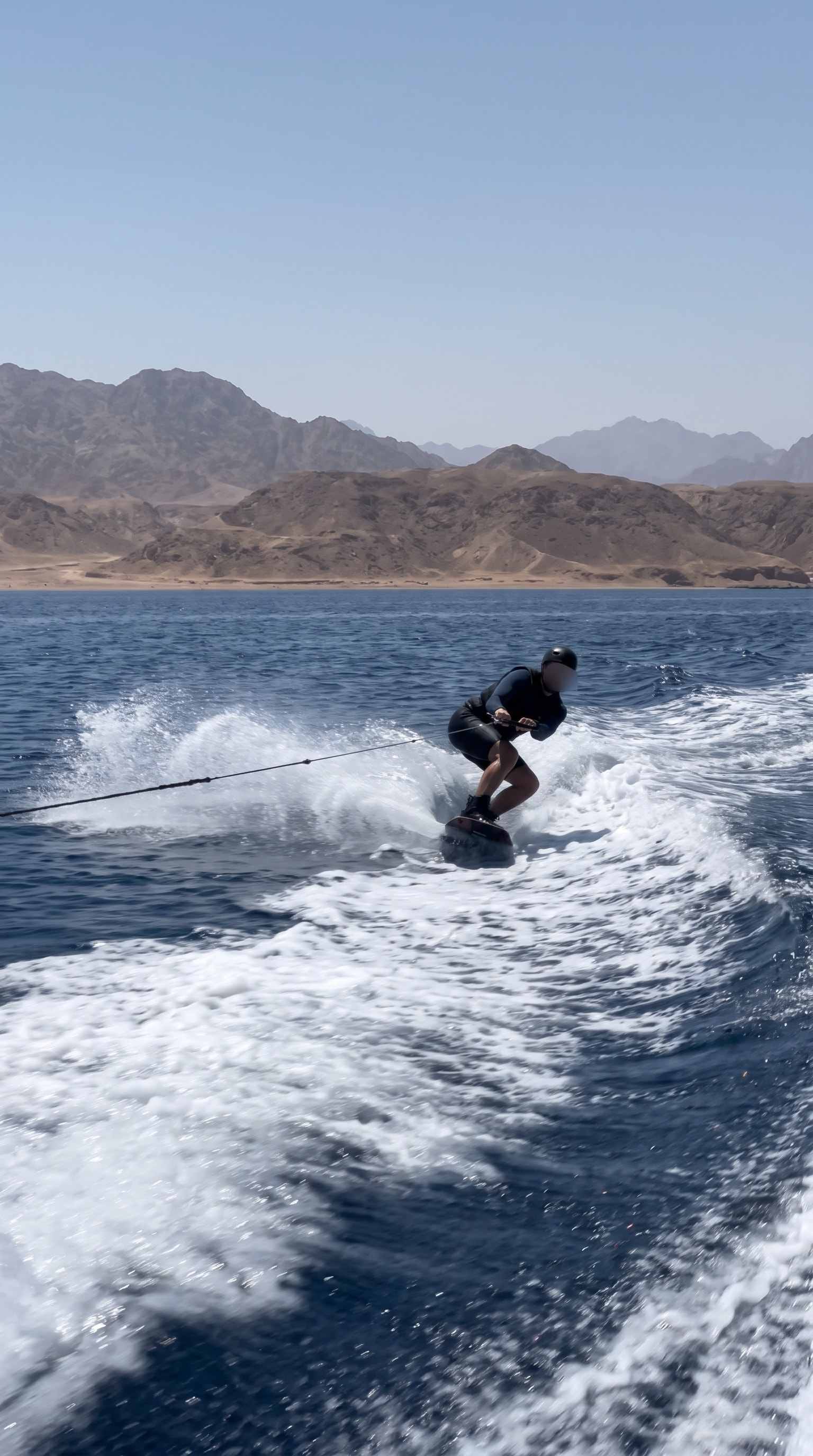 Wakeboarder carving a turn and throwing spray in front of the Sinai mountains
